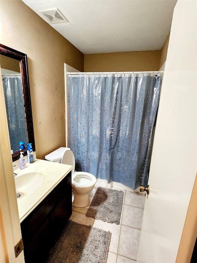 full bath with toilet, vanity, a textured ceiling, visible vents, and a textured wall