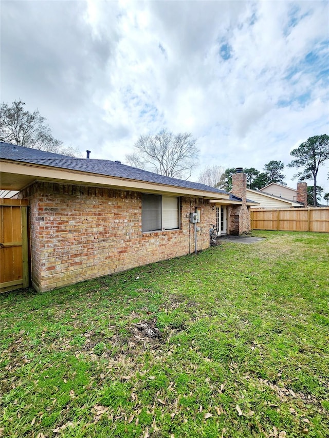 rear view of property with a yard, brick siding, and fence