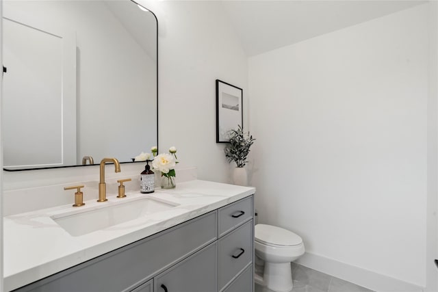 bathroom with toilet, lofted ceiling, vanity, and tile patterned flooring