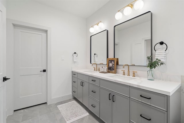 full bath with a sink, double vanity, baseboards, and tile patterned floors