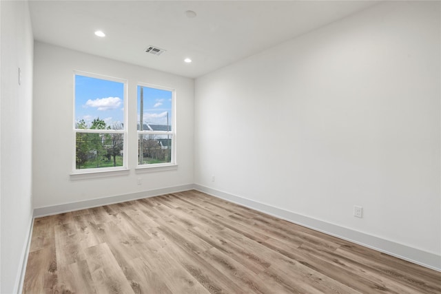 empty room featuring light wood-type flooring, visible vents, baseboards, and recessed lighting