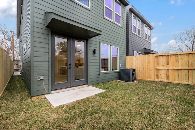 back of house featuring central air condition unit, french doors, a lawn, and a fenced backyard