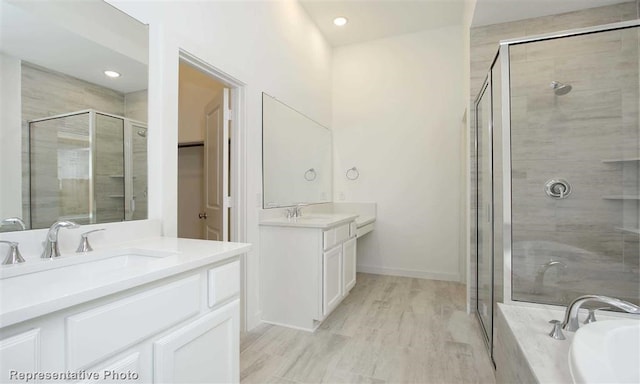 bathroom with a sink, two vanities, a stall shower, and a garden tub