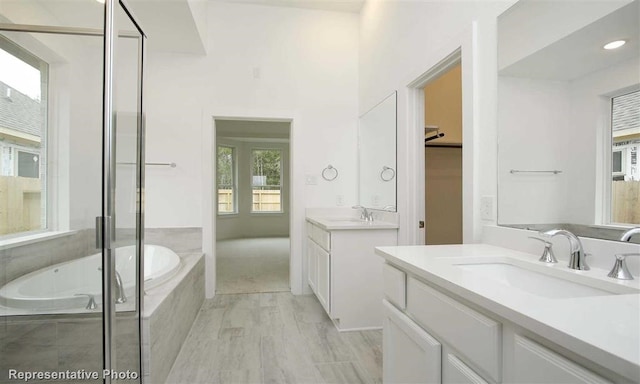 bathroom with a sink, two vanities, a garden tub, and a shower stall