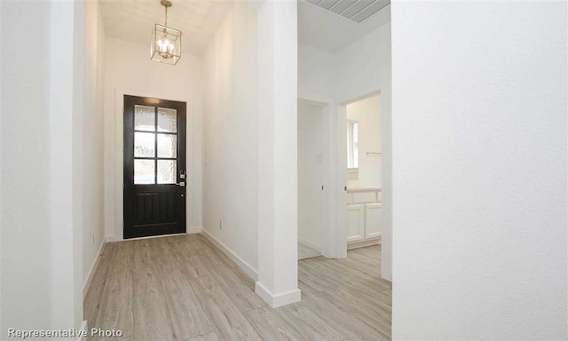 foyer entrance featuring baseboards, an inviting chandelier, visible vents, and wood finished floors
