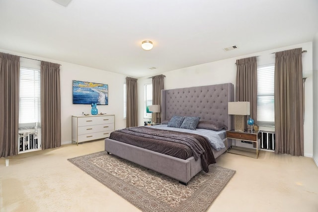 bedroom with multiple windows, visible vents, baseboards, and light carpet