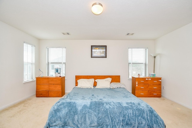 bedroom with light colored carpet, multiple windows, visible vents, and baseboards