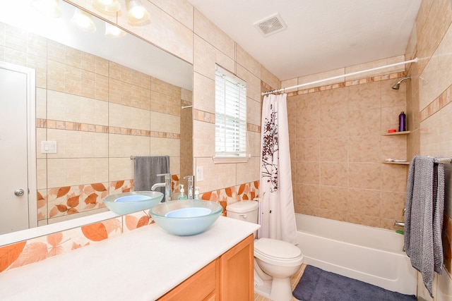 full bathroom featuring tile walls, toilet, visible vents, vanity, and shower / bathtub combination with curtain