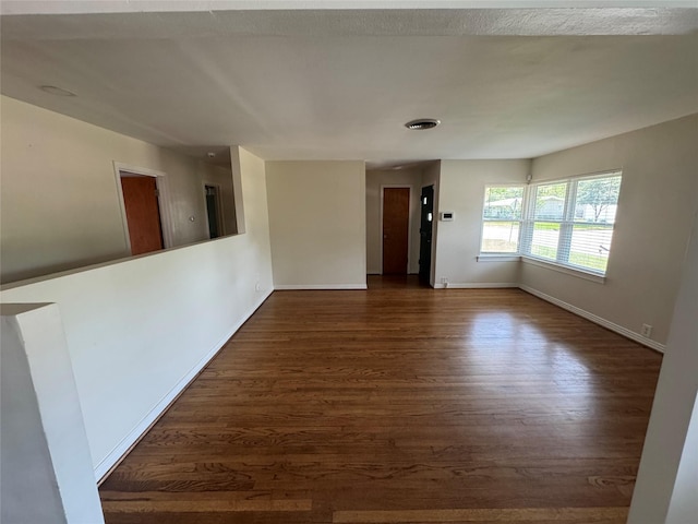 empty room with dark wood-style floors and baseboards