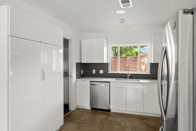 2218 Stonecrest, Houston, TX 77018 - kitchen featuring stainless steel appliances, a sink, concrete floors, backsplash, and white cabinets