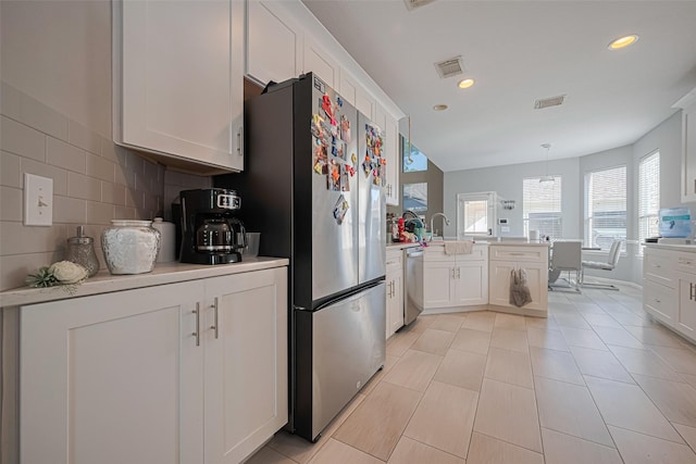 kitchen with a peninsula, white cabinetry, visible vents, light countertops, and appliances with stainless steel finishes