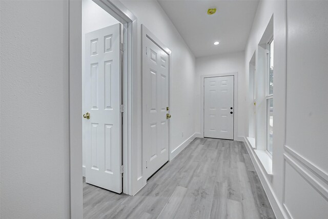 hall with light wood-style floors, baseboards, and recessed lighting