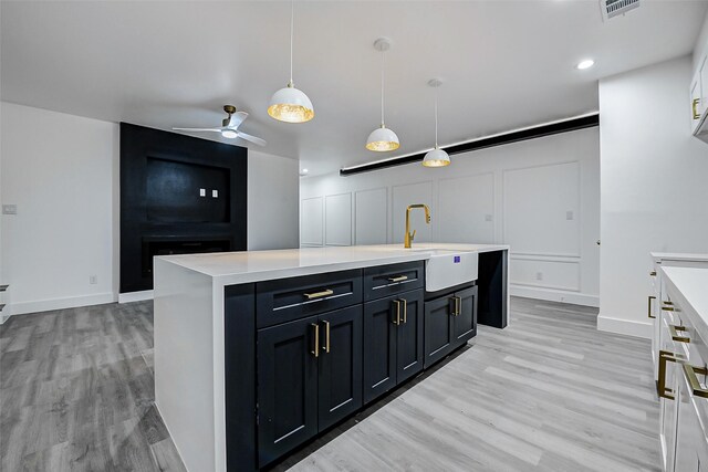 kitchen with a sink, light wood finished floors, light countertops, decorative light fixtures, and recessed lighting