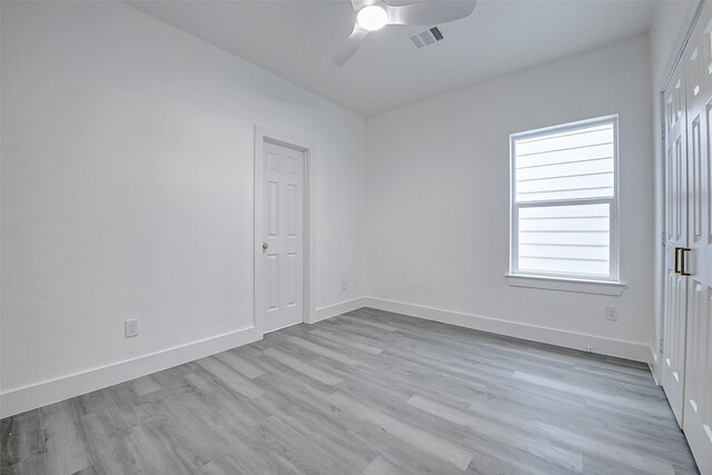 empty room with a ceiling fan, light wood-style floors, and baseboards