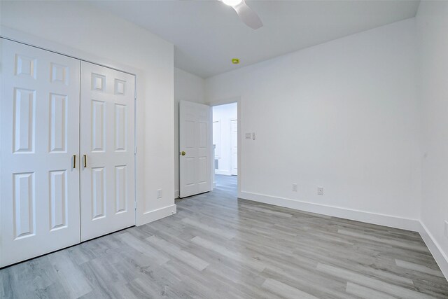 unfurnished bedroom featuring baseboards, light wood-type flooring, a closet, and ceiling fan
