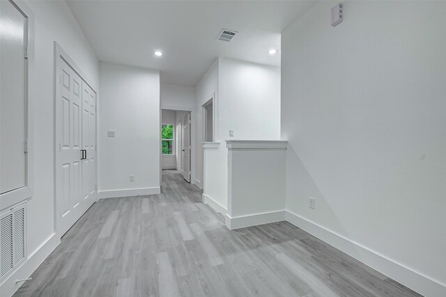 corridor featuring light wood-type flooring, recessed lighting, and baseboards