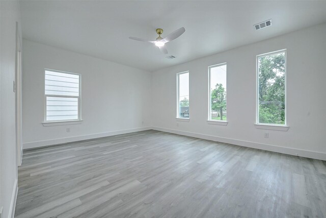 empty room featuring healthy amount of natural light, light wood finished floors, and baseboards