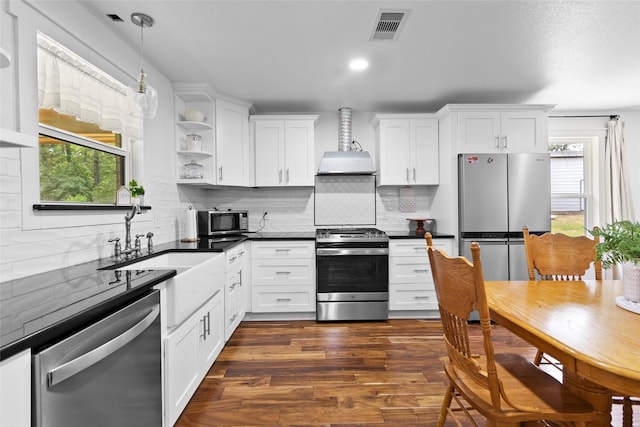 452 N Ghost Branch Rd, Trinity, TX 75862 - kitchen featuring dark countertops, wall chimney exhaust hood, visible vents, appliances with stainless steel finishes, and tasteful backsplash