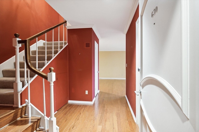 stairway featuring baseboards, visible vents, crown molding, and wood finished floors
