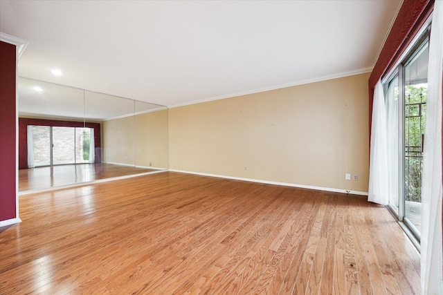 spare room with baseboards, light wood finished floors, and crown molding