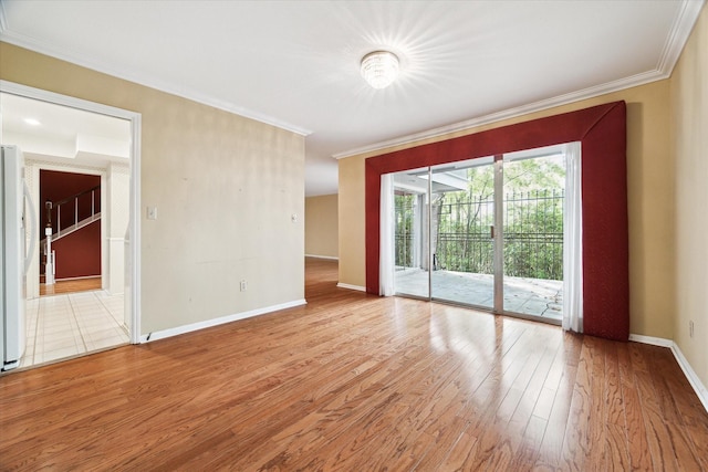 empty room featuring crown molding, wood finished floors, and baseboards