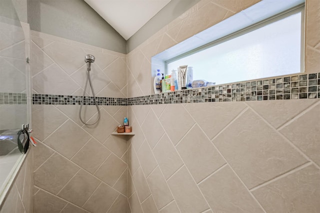 bathroom featuring vaulted ceiling and tiled shower