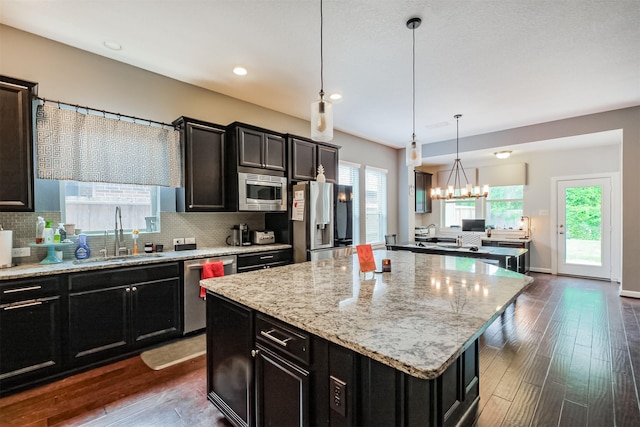 kitchen featuring a sink, stainless steel appliances, dark cabinetry, and a notable chandelier