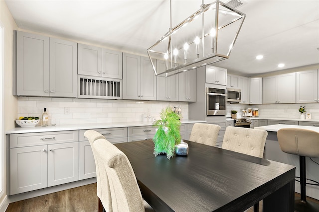 dining room with dark wood finished floors, a baseboard heating unit, and recessed lighting