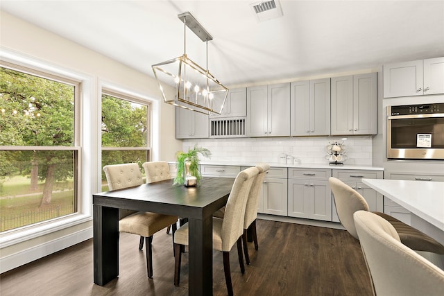 dining space with a chandelier, visible vents, and dark wood-type flooring