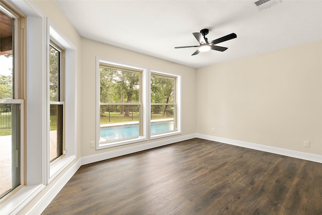spare room with baseboards, a ceiling fan, visible vents, and dark wood-style floors