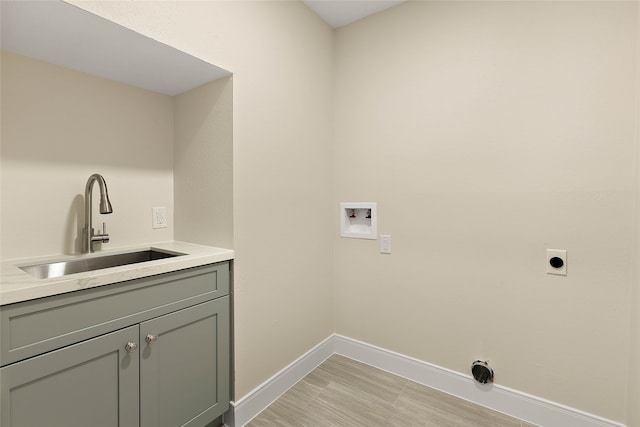 laundry area featuring electric dryer hookup, cabinet space, washer hookup, a sink, and baseboards