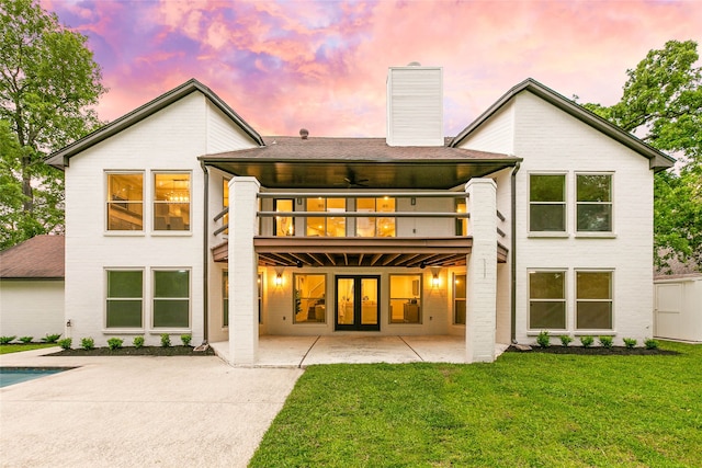 rear view of property featuring a lawn, a chimney, french doors, a patio, and a deck