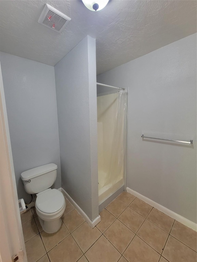 bathroom featuring toilet, baseboards, visible vents, a shower stall, and tile patterned flooring
