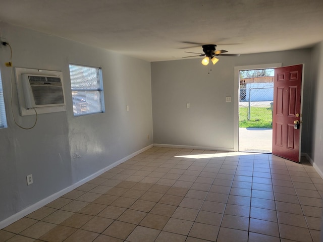 empty room featuring light tile patterned floors, baseboards, a ceiling fan, and a wall unit AC