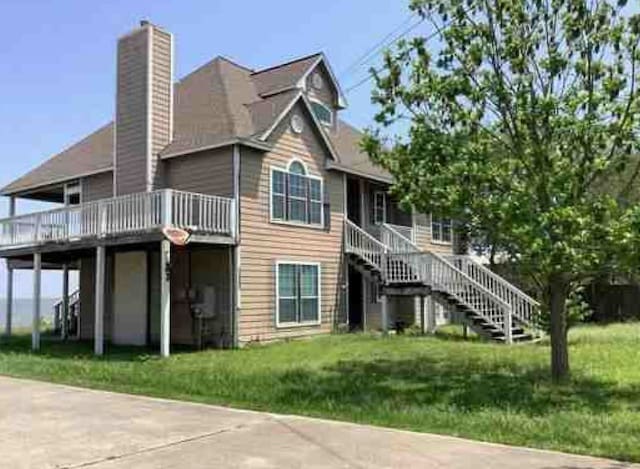 115 8th St, San Leon, TX 77539 - rear view of property with a chimney, stairs, a deck, and a lawn