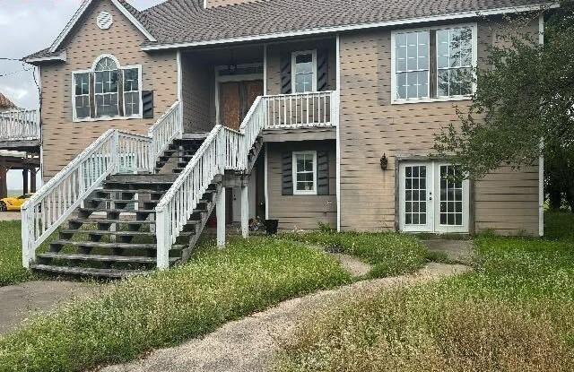 115 8th St, San Leon, TX 77539 - rear view of house with stairway and french doors