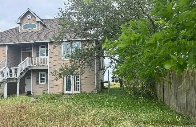 115 8th St, San Leon, TX 77539 - back of property with fence, stairs, and a lawn
