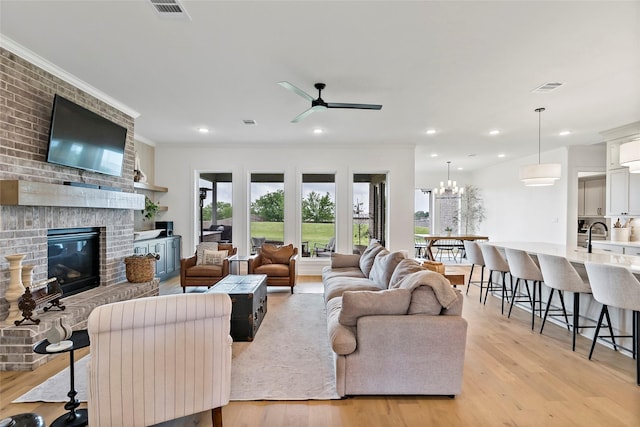 4233 Padova Cir, College Station, TX 77845 - living area featuring light wood finished floors, visible vents, ceiling fan with notable chandelier, and a brick fireplace
