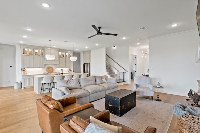 4233 Padova Cir, College Station, TX 77845 - living room featuring light wood-style floors, stairs, ceiling fan with notable chandelier, and recessed lighting