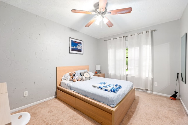 carpeted bedroom with baseboards, ceiling fan, and a textured wall