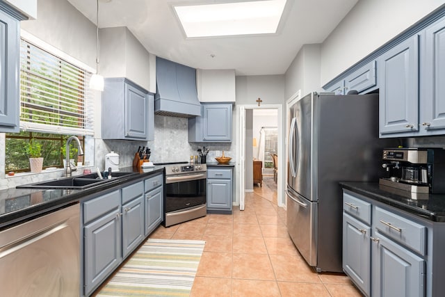 kitchen with a sink, backsplash, light tile patterned floors, custom range hood, and appliances with stainless steel finishes