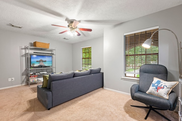 carpeted living area featuring a textured ceiling, visible vents, baseboards, and ceiling fan