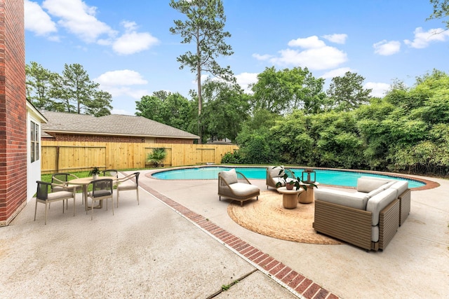 view of pool featuring a patio area, a fenced backyard, and view of wooded area