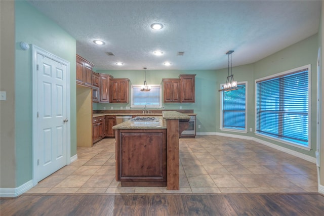 kitchen featuring baseboards, a healthy amount of sunlight, a chandelier, and a center island
