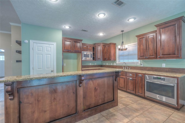 kitchen with a sink, stainless steel appliances, pendant lighting, and visible vents
