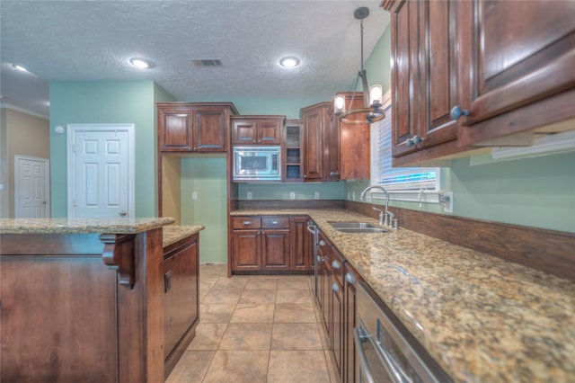 kitchen with light stone countertops, decorative light fixtures, visible vents, stainless steel microwave, and a sink