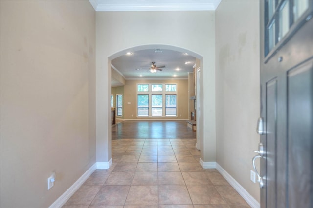 entrance foyer featuring a ceiling fan, baseboards, crown molding, and arched walkways