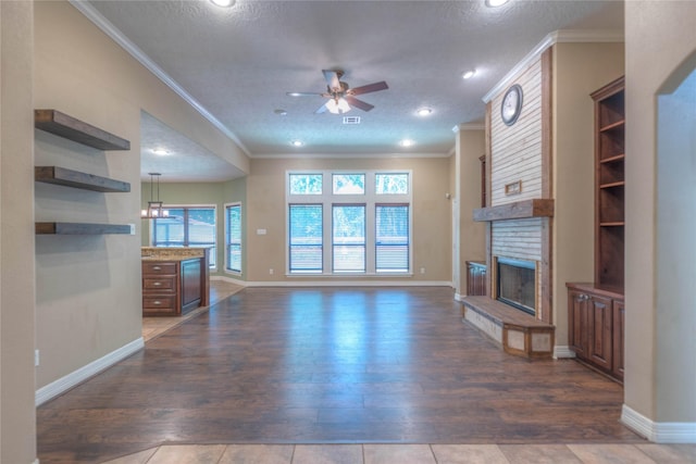 unfurnished living room with a brick fireplace, crown molding, ceiling fan, dark wood-style floors, and recessed lighting