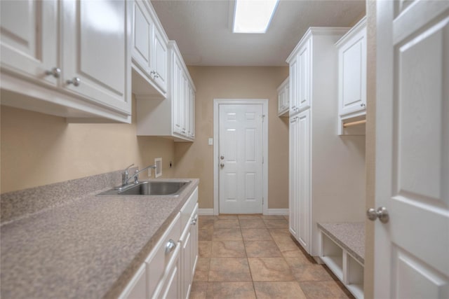 washroom featuring a sink, cabinet space, washer hookup, and baseboards