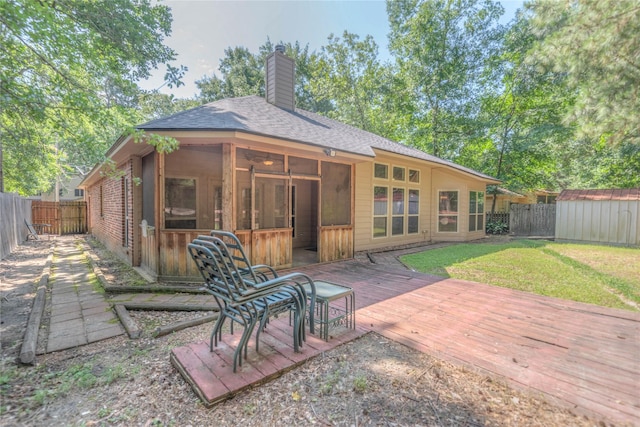 back of property with a chimney, a wooden deck, a storage shed, and a fenced backyard